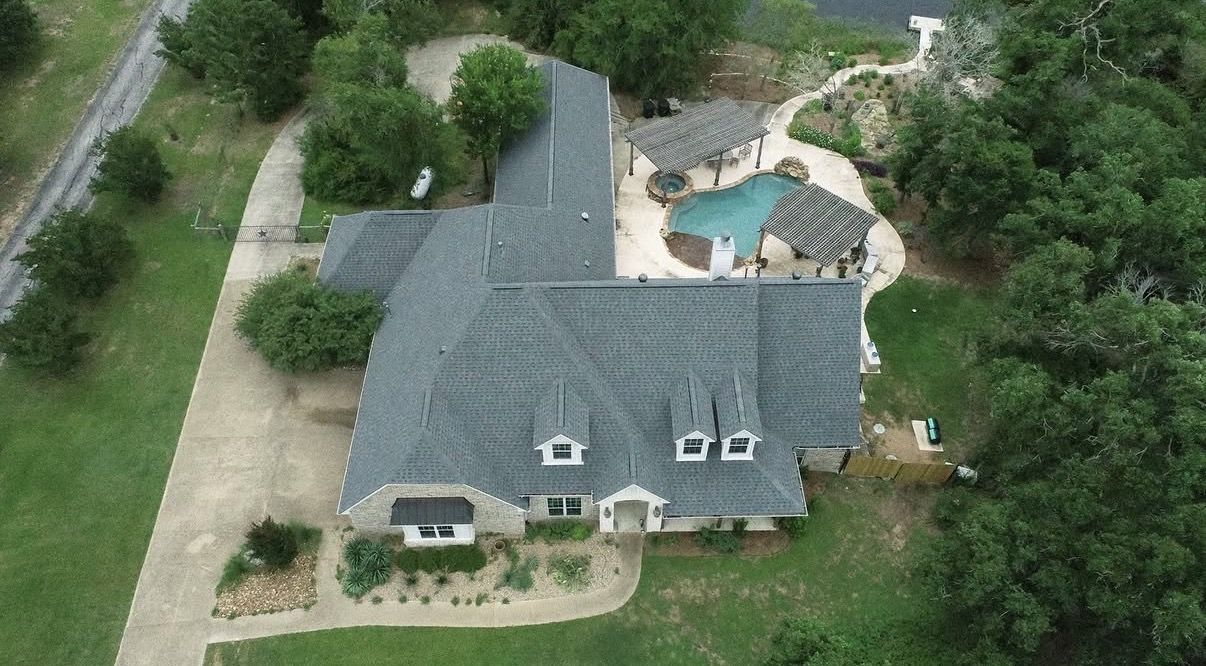 Aerial view of a full shingle roof replacement on a Texas home with pool